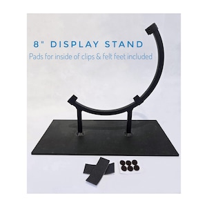 May include: Black metal display stand, 8 inches tall, with a curved top and rectangular base. Includes pads for clips and felt feet. Text on the image reads "8" DISPLAY STAND Pads for inside of clips & felt feet included."
