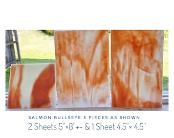 May include: Three rectangular sheets of salmon-colored Bullseye glass with white marbled patterns. The set includes two sheets measuring 5 inches by 8 inches and one sheet measuring 4.5 inches by 4.5 inches, as labeled in the text below the items.