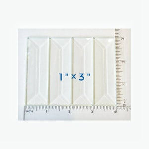 May include: Four clear glass rectangular tiles with beveled edges arranged side by side. A ruler is visible along the bottom and right edges, confirming each tile measures 1 inch by 3 inches as indicated by the text 1" x 3" in the center.