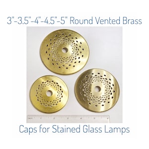 May include: Three round, vented brass caps for stained glass lamps. Sizes range from 3 to 5 inches in diameter. Each cap features a central hole and a decorative, spiraling pattern of small perforations.