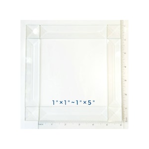 May include: Clear glass square with beveled edges, measuring approximately 1" x 1" to 1" x 5". The glass has a reflective quality and is set against a white background. A ruler is placed along the side for measurement.