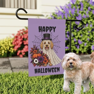 Puede incluir: Una bandera de jardín rectangular de color morado con el gráfico de un perro vestido con un disfraz de fantasma blanco y un sombrero de copa negro. Detrás del perro hay una telaraña. El texto HAPPY HALLOWEEN aparece en la bandera.