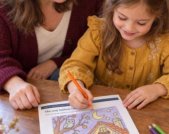Könnte beinhalten: Ein weißes Malblatt mit dem Titel The cosy lantern cot, das ein Haus, Kürbisse, eine Eule und eine Mondsichel zeigt. Die Illustration ist teilweise mit orangefarbenen, violetten und grünen Stiften ausgemalt, ein orangefarbener Stift wird benutzt.