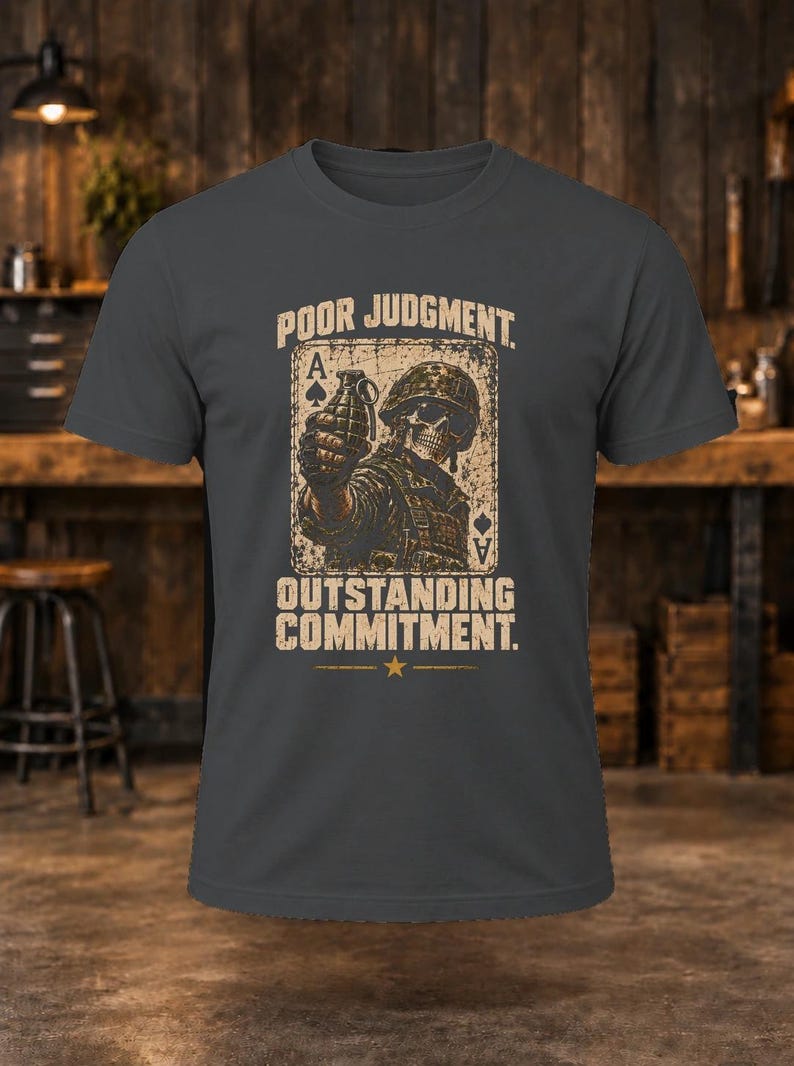 Puede incluir: Una camiseta gris carb&oacute;n con un gr&aacute;fico de un soldado esqueleto con casco sosteniendo una granada, sobre un fondo de carta de as de picas. El texto dice POOR JUDGMENT en la parte superior y OUTSTANDING COMMITMENT en la parte inferior.