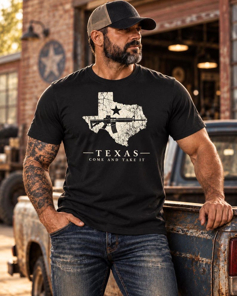 May include: A black short-sleeve t-shirt featuring a white distressed graphic of the state of Texas with a star and a rifle silhouette. Below the graphic, the text reads TEXAS and COME AND TAKE IT in white capital letters.