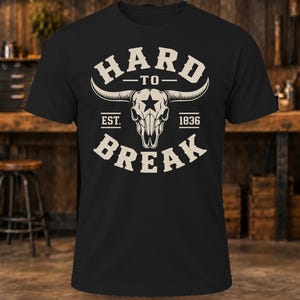 May include: A black short-sleeve t-shirt featuring a white graphic of a longhorn steer skull with a star on the forehead. The text reads HARD TO BREAK with EST. 1836 positioned on either side of the skull in a distressed, vintage-style font.