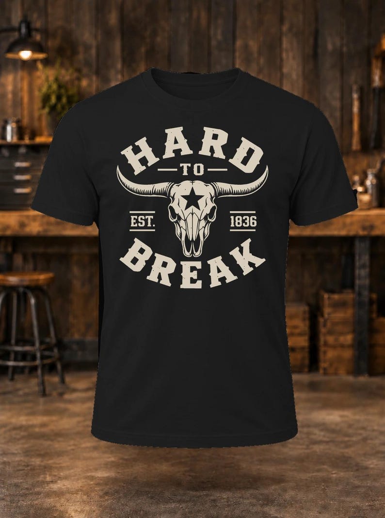 May include: A black short-sleeve t-shirt featuring a white graphic of a longhorn steer skull with a star on the forehead. The text reads HARD TO BREAK with EST. 1836 positioned on either side of the skull in a distressed, vintage-style font.