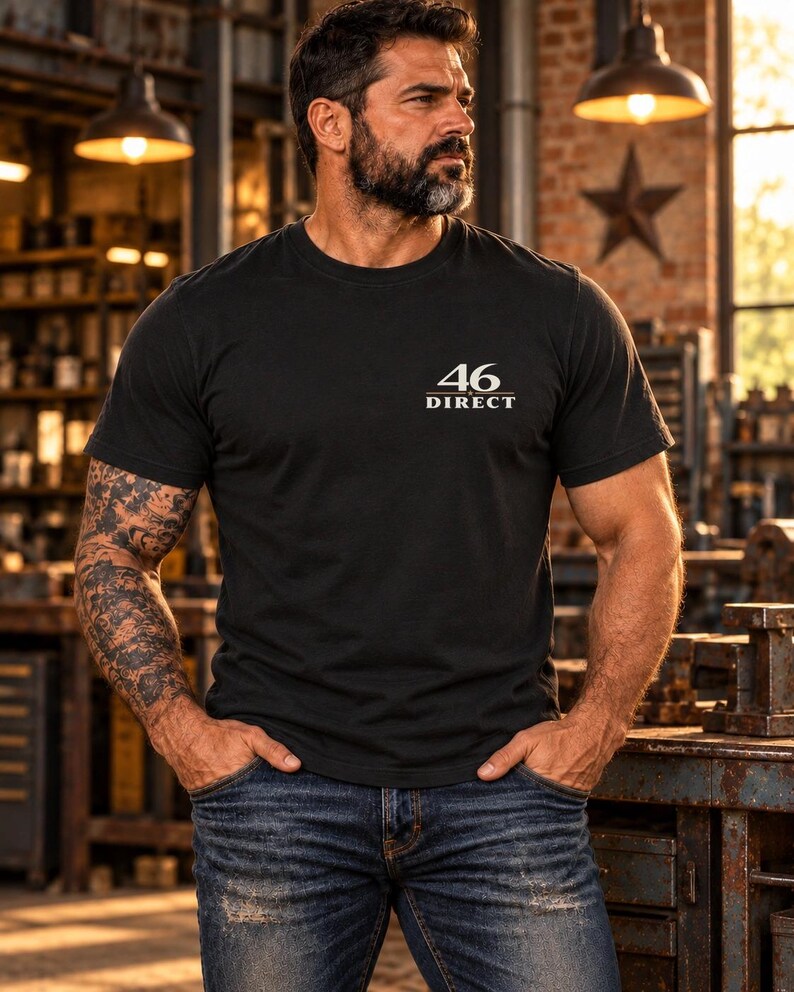 May include: A black short-sleeved crew neck t-shirt featuring the text 46 DIRECT printed in white on the upper left chest area. The shirt is paired with blue denim jeans that have a distressed finish and visible wear along the pockets.