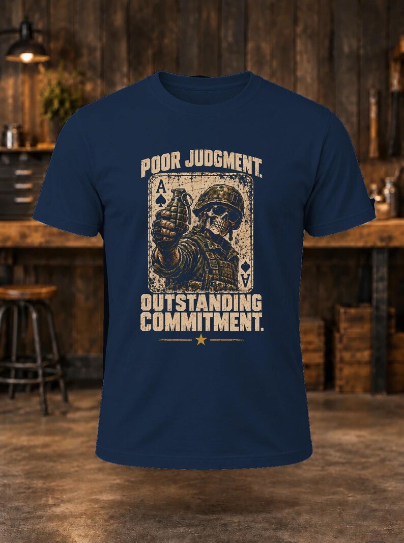 Puede incluir: Una camiseta azul marino con un gr&aacute;fico de un soldado esqueleto con casco sosteniendo una granada, sobre un fondo de carta de as de picas. El texto dice POOR JUDGMENT y OUTSTANDING COMMITMENT con una estrella debajo.
