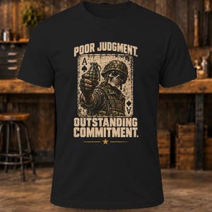 Puede incluir: Una camiseta negra de manga corta con un gr&aacute;fico de un soldado esqueleto con casco sosteniendo una granada, sobre un fondo de carta de as de picas. El texto dice POOR JUDGMENT y OUTSTANDING COMMITMENT con una estrella debajo.