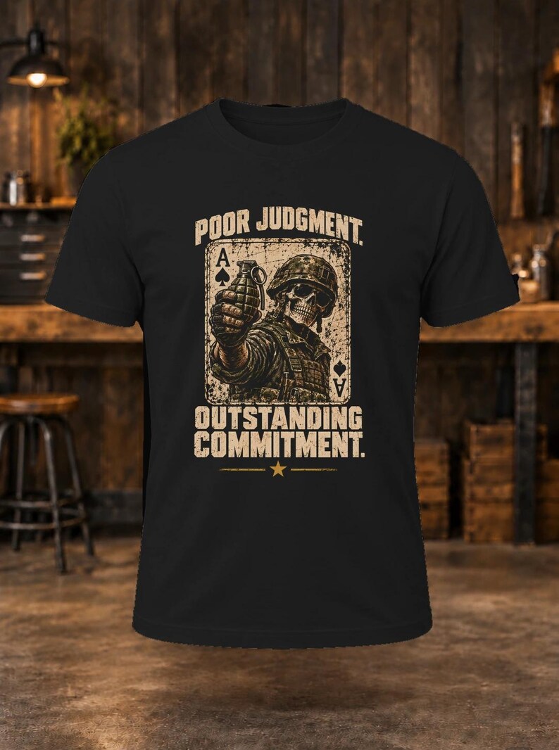 Puede incluir: Una camiseta negra de manga corta con un gr&aacute;fico de un soldado esqueleto con casco sosteniendo una granada, sobre un fondo de carta de as de picas. El texto dice POOR JUDGMENT y OUTSTANDING COMMITMENT con una estrella debajo.