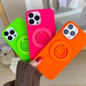 Peut inclure: Trois coques de téléphone aux couleurs vives : vert néon, rose vif et orange. Chaque coque possède un support de bague assorti à l'arrière. Les coques sont maintenues, mettant en valeur leurs couleurs vives et leur design élégant. Accessoire moderne.