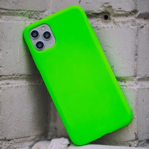 K&ouml;nnte beinhalten: Eine leuchtend gr&uuml;ne Handyh&uuml;lle mit einem Ausschnitt f&uuml;r das Kameraobjektiv. Die H&uuml;lle ist aus weichem, flexiblem Material gefertigt und hat eine glatte Oberfl&auml;che.