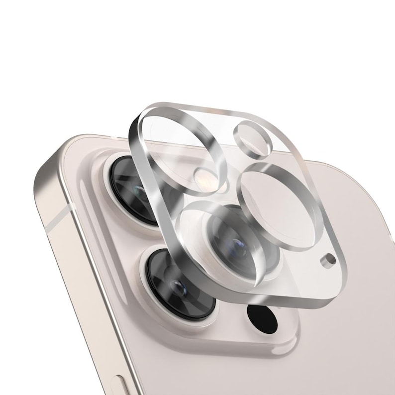 Puede incluir: Un protector de lente de c&aacute;mara transparente para un tel&eacute;fono inteligente. El protector est&aacute; hecho de vidrio templado y tiene un marco plateado. Est&aacute; dise&ntilde;ado para proteger la lente de la c&aacute;mara de ara&ntilde;azos y da&ntilde;os.