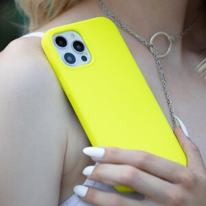 May include: A bright yellow phone case with a camera lens cutout. The case is made of silicone and has a smooth, matte finish.