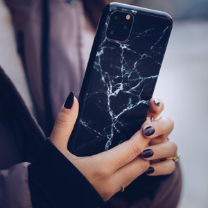 May include: A black phone case with a white marble pattern. The case has a triple camera lens on the back.