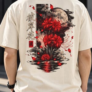 以下が含まれることがあります： 背面に鮮やかな赤い彼岸花、暗い雲、水面に映る満月が描かれたクリーム色の半袖Tシャツ。左側には縦書きの日本語の文字がプリントされており、全体的に落ち着いた色合いのデザインが特徴です。