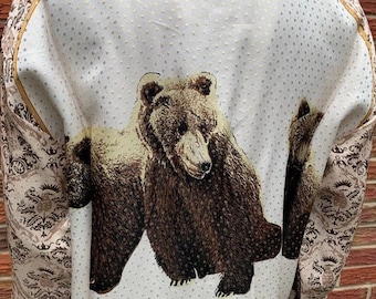 May include: A white button-up shirt with a brown and gold patterned design. The shirt features a large brown bear print on the back.
