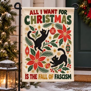 May include: A cream-colored garden flag featuring the text "ALL I WANT FOR CHRISTMAS IS THE FALL OF FASCISM" in green and red. The design includes two black cats playing with red and green Christmas ornaments, poinsettias, and pine branches.