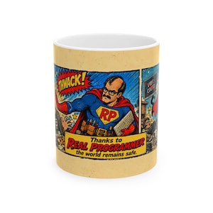 May include: A white ceramic mug featuring a comic book style illustration of a superhero with a mustache and glasses wearing a blue suit with an RP emblem, holding a keyboard, with the text THWACK and Thanks to REAL PROGRAMMER the world remains safe.