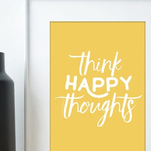 May include: A yellow framed print with white text that reads "think happy thoughts".