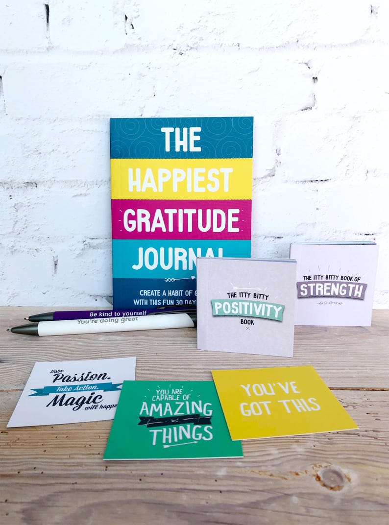May include: A set of motivational and inspirational journals and cards. The journals are titled "The Happiest Gratitude Journal" and "The Itty Bitty Positivity Book". The cards have phrases like "Have Passion. Take Action. Magic will happen" and "You've Got This".