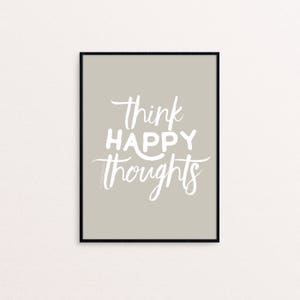 May include: A framed print with a light gray background and white text that reads "think happy thoughts".
