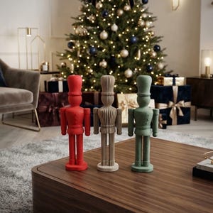 May include: Three standing nutcracker figurines in a row, each featuring a tall hat and uniform-style design. The left figure is solid red, the centre figure is beige with a ribbed texture, and the right figure is a muted sage green colour.