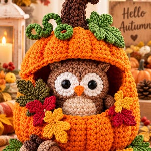 Può includere: Una zucca arancione all'uncinetto con un gambo marrone, foglie verdi e viticci. All'interno della zucca siede un piccolo gufo marrone e crema con occhi neri e becco arancione. Due ghiande marroni e foglie all'uncinetto decorano la base.