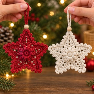May include: Two star-shaped ornaments crafted from crochet yarn, one in deep red and one in off-white. Each star features a central floral motif, a scalloped edge, and a small wooden bead attached to a matching loop for hanging purposes.