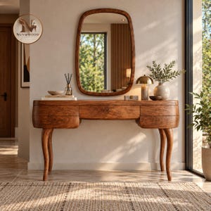 May include: A wooden vanity table with a smooth, curved design, featuring three drawers and four slender, tapered legs. Above the table hangs a matching rounded rectangular mirror. The wood has a rich, warm brown grain and polished finish.