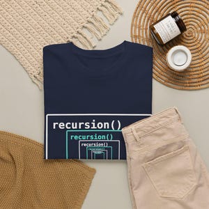 Könnte beinhalten: Ein dunkelblaues T-Shirt mit einem weißen und hellblauen Grafikdruck des Wortes recursion(), das mehrfach in rechteckigen Rahmen in sich selbst verschachtelt ist und eine visuelle Darstellung einer rekursiven Programmierfunktion bildet.