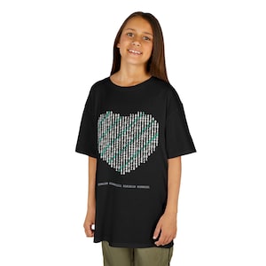 May include: A black short-sleeved t-shirt featuring a large heart graphic composed of white and teal binary code digits. Below the heart, a small line of white binary code text is printed. The shirt has a crew neckline and a relaxed fit.
