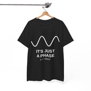 Könnte beinhalten: Ein schwarzes T-Shirt mit kurzen Ärmeln und einer weißen Grafik einer Sinuswelle. Unter der Welle steht der Text IT'S JUST A PHASE in weißen Großbuchstaben, gefolgt von der mathematischen Gleichung y = sin(x), die in Weiß aufgedruckt ist.