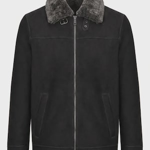 May include: A black jacket featuring a dark gray faux fur collar, a full-length silver-tone front zipper, and two side pockets. The collar includes a small buckle strap detail at the neck, and the jacket has long sleeves with straight cuffs.