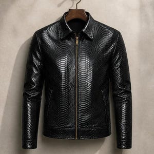 May include: A black jacket featuring a textured snakeskin-like pattern throughout the exterior. The garment includes a standard collar, long sleeves, and a central vertical zipper closure with a metallic finish, hanging on a wooden hanger.