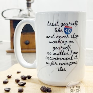 May include: White ceramic mug with the text "treat yourself like 40 and never stop working on yourself no matter how inconvenient it is for everyone else." The mug has a large handle and is sitting on a wooden cutting board with coffee beans.