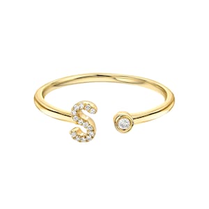 Puede incluir: Un anillo de oro con una letra "S" engastada con diamantes y un solo diamante en la banda.