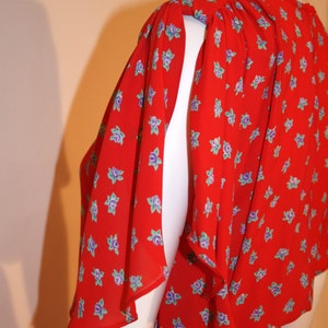 May include: A red dress with a floral print and ruffled sleeves. The dress is made of a lightweight fabric and has a loose fit.
