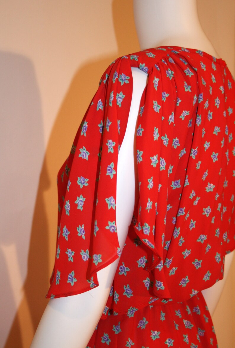 May include: A red dress with a floral print and ruffled sleeves. The dress is made of a lightweight fabric and has a loose fit.
