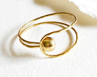 May include: A gold-toned double-ring bracelet with a hammered finish and a round orb accent.
