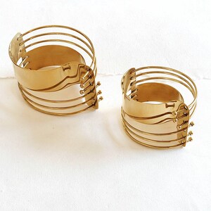 Peut inclure: Deux bracelets en métal doré avec un design géométrique unique. Les bracelets sont composés de plusieurs bandes entrelacées et ont une finition texturée.