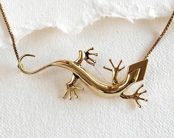 Peut inclure: Un collier en or avec un pendentif en forme de lézard. Le lézard est détaillé avec des griffes et une longue queue.