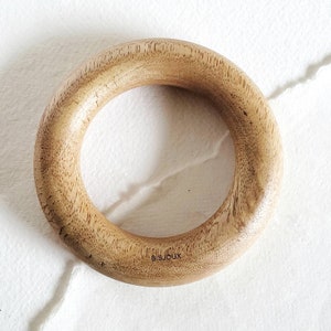 May include: A light brown wooden ring with the word "BISJOUX" engraved on the side.