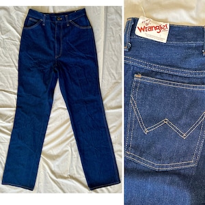 K&ouml;nnte beinhalten: Dunkelblaue Wrangler Jeans aus Denim. Die Jeans haben eine hohe Taille, ein gerades Bein und ein klassisches F&uuml;nf-Taschen-Design. Die Ges&auml;&szlig;tasche hat die Wrangler "W"-Naht. Die Jeans sind neu mit Etikett.