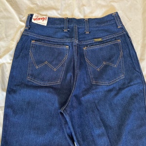 K&ouml;nnte beinhalten: Dunkelblaue Jeans aus Denim mit dem Markenetikett Wrangler. Die Jeans haben einen klassischen F&uuml;nf-Taschen-Stil mit der charakteristischen Wrangler-Naht auf den Ges&auml;&szlig;taschen. Die Jeans sind aus strapazierf&auml;higem Denim-Material.