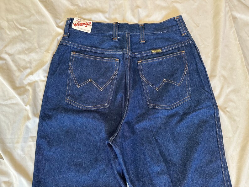 K&ouml;nnte beinhalten: Dunkelblaue Jeans aus Denim mit dem Markenetikett Wrangler. Die Jeans haben einen klassischen F&uuml;nf-Taschen-Stil mit der charakteristischen Wrangler-Naht auf den Ges&auml;&szlig;taschen. Die Jeans sind aus strapazierf&auml;higem Denim-Material.