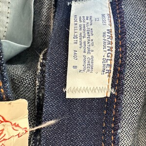 K&ouml;nnte beinhalten: Nahaufnahme einer dunkelblauen Jeans mit einem Etikett mit der Aufschrift "Wrangler No-Fault Denim". Das Etikett enth&auml;lt auch Waschanweisungen und den Text "Made in U.S.A.2G TR". Die Jeans hat Gr&ouml;&szlig;e 12.
