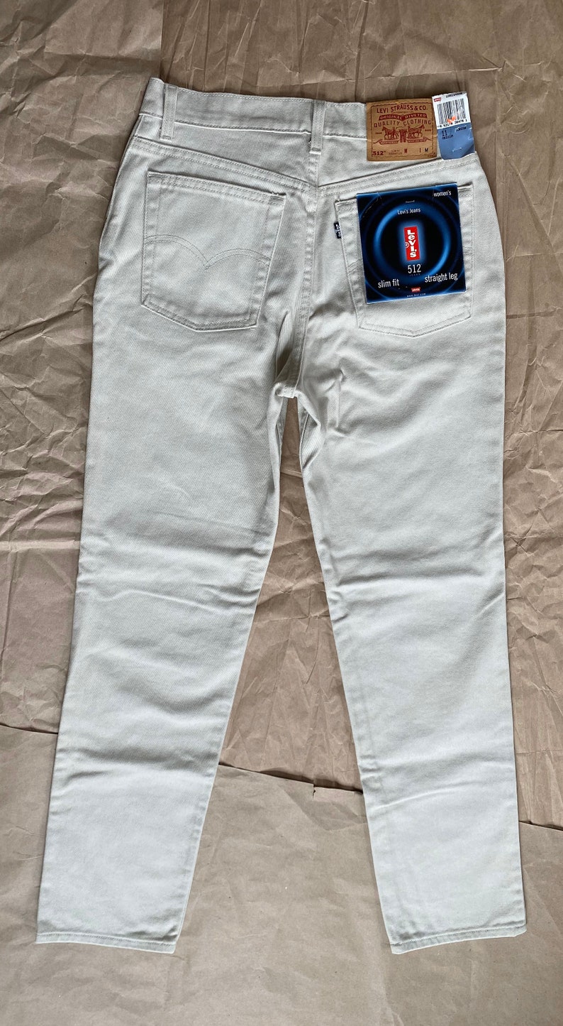 May include: A pair of light beige straight leg jeans with a Levi's 512 slim fit label on the back pocket.