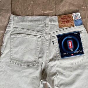 May include: A pair of light beige jeans with a back pocket and a Levi's tag. The tag says "Levi's Jeans" and "512 slim fit straight leg".